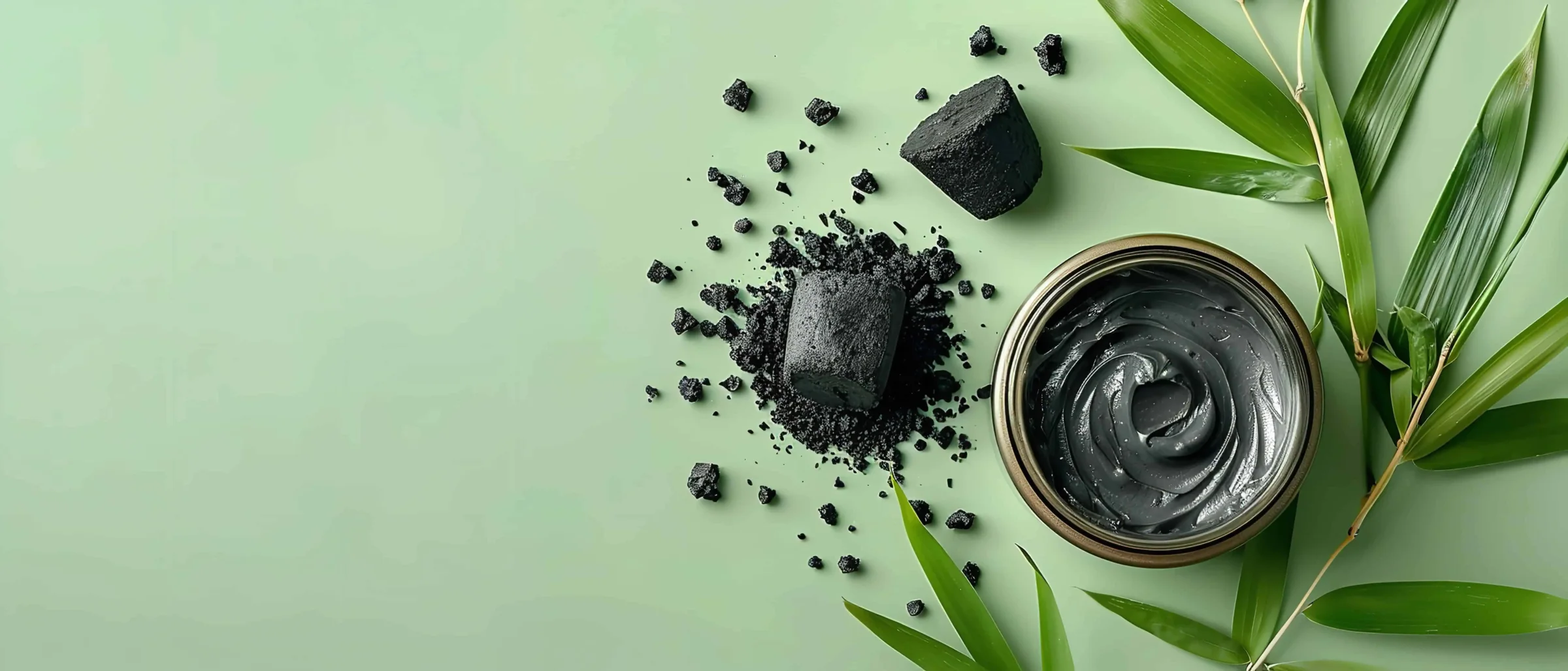 Blocs et éclats de shilajit brut à côté d'un pot de résine purifiée, sur fond vert avec des feuilles